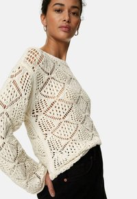 Krämfärgad virkadröja med ett öppet stickat mönster i geometriska former, lång ärm och en avslappnad passform.