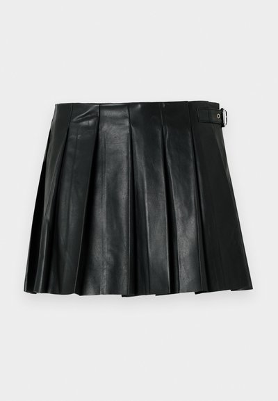 Mini-jupe plissée en simili cuir noir avec détail boucle latérale sur fond uni.