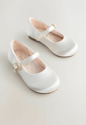 Baltas satinēts baleta kurpes ar apaļu purngalu, regulējamu jostu un dekoratīvu zelta akcentu. Mīksts rozā iekšpuse un teksturēti zoli.