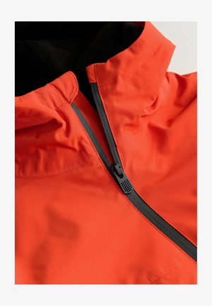 Oranžová vodoodolná bunda s vysokým golierom, čiernym zipsom a hladkou textúrou; obsahuje kontrastné čierne akcenty a detaily šitia.