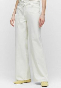 Breda vita denimbyxor med dragsko i midjan, har framfickor och en slät yta. Matchas med ljusgula ballerinas.