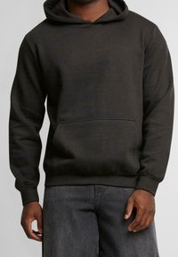 Sudadera gris oscuro hecha de una mezcla de algodón. Cuenta con un bolsillo delantero, capucha con cordón ajustable, y puños y dobladillo acanalados.