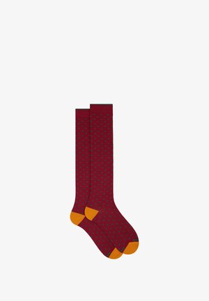 Bordeauxfarbene knielange Socken mit grünen Punkten, orangefarbigen Akzenten an der Zehe und Ferse. Hergestellt aus einem weichen, dehnbaren Material.