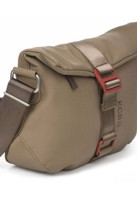 Bruine nylon boodschappentas met een omslagklep, verstelbare schouderriem, rode metalen accenten en een subtiel logodetail.