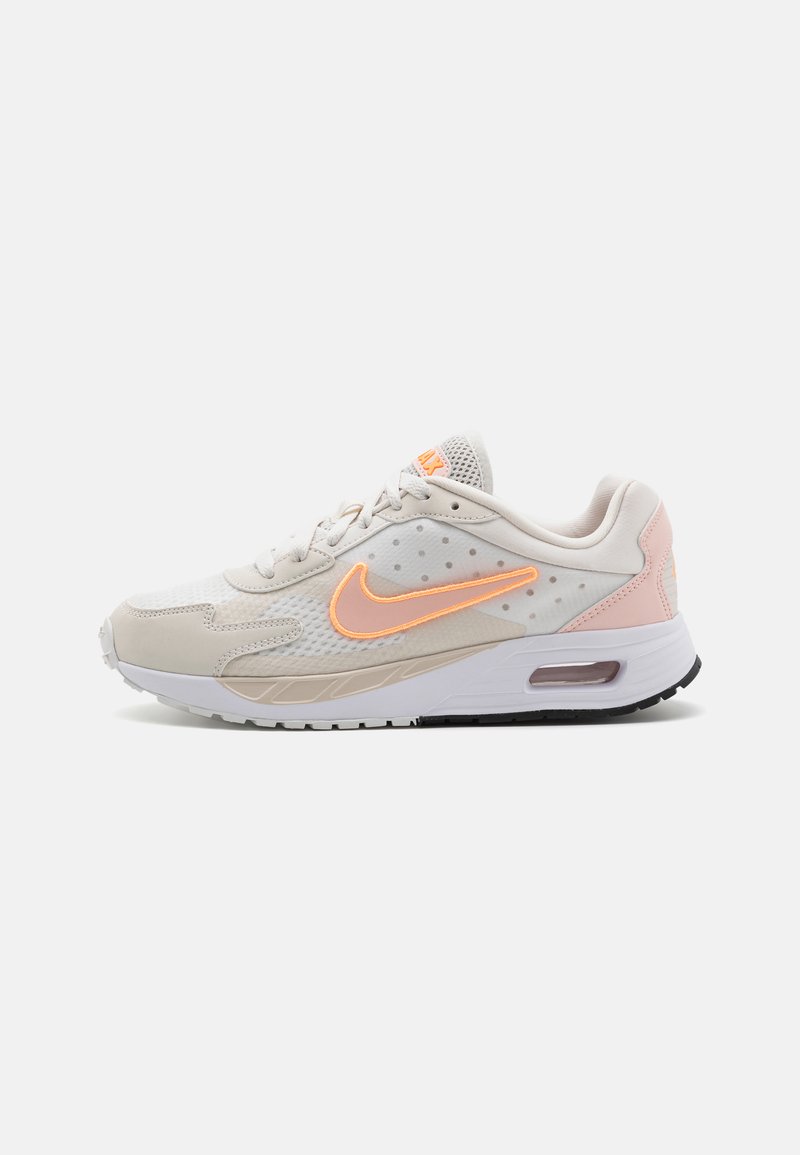 Des chaussures Nike Air Max, avec un dessus en mesh beige clair, des détails accentués en orange, un design texturé et un amorti à air visible dans la semelle.