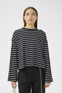 Crtni crno-bijeli cropped dugouhati top s okruglim izrezom i širokim rukavima, kombiniran s crnim hlačama s detaljem lanaca.