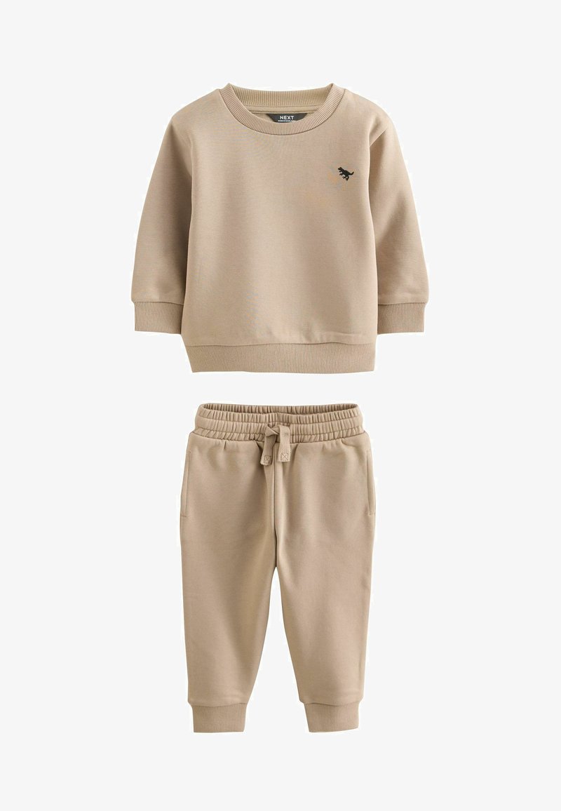 Beige cotton sweatshirt with ribbed cuffs and hem, featuring a small black logo. Matching beige joggers with elastic waistband and cuffs.