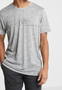 Grå t-shirt med kort ärm gjord av lättviktig tyg, med en enkel linjeteckning av en cykel på framsidan. Slät textur, avslappnad passform.