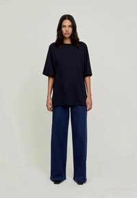 Ναυτικού χρώματος oversized T-shirt με κοντά μανίκια, συνδυασμένο με φαρδιά παντελόνια σε σκούρο μπλε χρώμα, και τα δύο κατασκευασμένα από ελαφρύ ύφασμα, εμφανίζονται σε ουδέτερο φόντο.