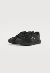 Schwarze Sportschuhe aus Mesh- und Synthetikmaterialien, mit strukturierten Sohlen, Schnürdesign und einem geschwungenen Logoakzent in Grau.