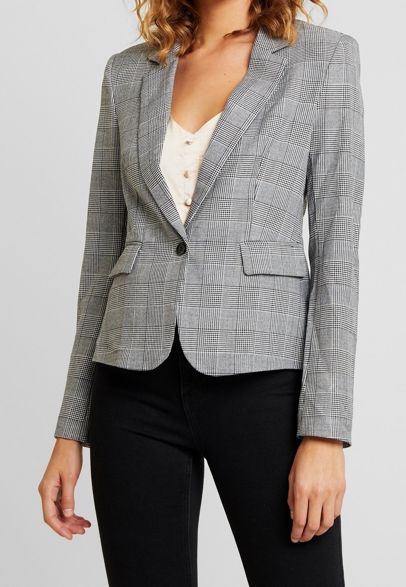 Karierte Blazer in Grautönen, mit abgesetztem Revers, einreihigem Knopfverschluss und zwei Vorderaschen. Glatte Textur mit strukturierter Form.