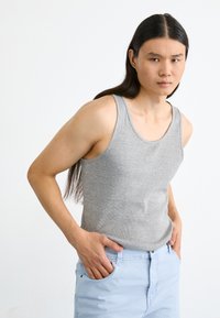 Débardeur en coton gris avec une texture côtelée, doté de larges emmanchures et d'un col rond, associé à un pantalon bleu clair.
