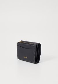 Black leather wallet with gold hardware, zip pocket, and front card slot. Accented with white stitching. Compact rectangular shape.