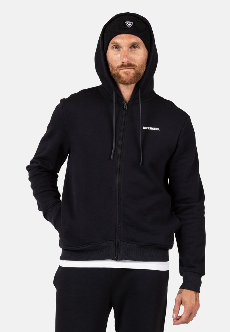 Schwarze Zip-Up-Hoodie aus weichem Material, mit einem vorderen Reißverschluss, einer Kordelzugkapuze und einem kleinen weißen Logo auf der Brust.