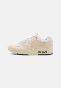 Nike Air Max 1 kedas baltā, gaiši persiku un krēmkrāsas. Iespējas ir ādas un sieta augšdaļa, mīkstināta apkakle un redzamā gaisa vienība zole.