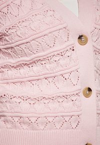 Cardigan rosa lavorato a maglia con motivi intricati, dotato di scollatura a V, bordi a coste e grandi bottoni beige.