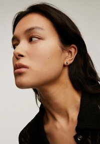 Pendientes de plata en forma de gota con un diseño elegante y alargado. Uno presenta un pequeño perno, mientras que el otro tiene un delgado acento colgante recto.