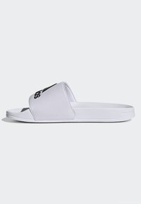 Sandal in slide bianco con cinturino testurizzato e suola bianca; presenta un logo nero sul davanti. Finitura liscia e design aperto.