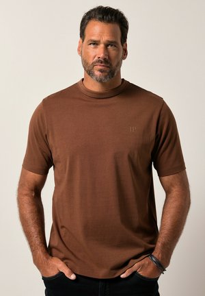 Camiseta marrón de manga corta con cuello redondo, que presenta un logo sutil en la esquina superior izquierda. Tejido suave y texturizado.