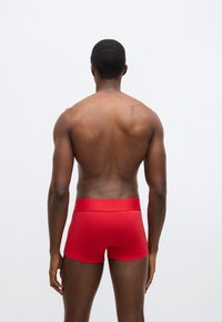 Červené bavlnené boxerky s hladkou textúrou, s mäkkým pásom a priliehavým strihom, zobrazené zozadu na neutrálnom pozadí.