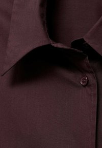 Camisa burdeos de botonadura frontal con cuello estructurado, textura suave, bolsillo en el pecho y botones en contraste para mayor detalle.