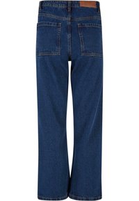Jean denim bleu foncé à jambes larges avec deux poches plaquées à l'arrière et une étiquette de marque en cuir marron sur la ceinture.