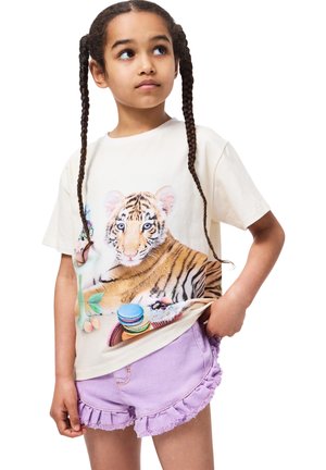 Cremefarvet T-shirt med tiger grafik og farverigt makaron design. Parret med lyse lilla denimshorts med frynset, bølget kant.