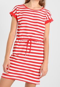 Punainen ja valkoinen raidallinen lyhythihainen mekko, jossa on pyöreä kaula-aukko, lyhyet hihat ja kireä vyötärö, varustettu kiristysnauhalla ja pehmeällä pinnalla.