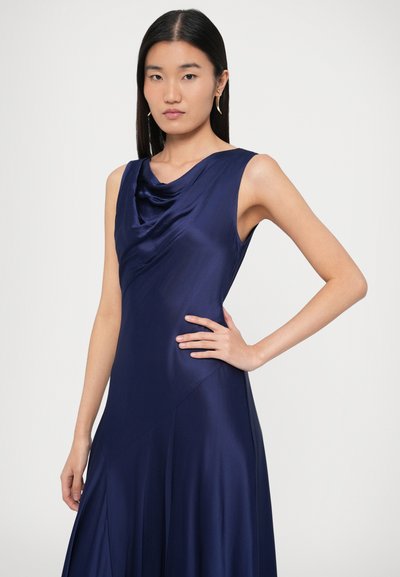 Tengerészkék szaténruha, csuklyás kivágással, ujjatlan kialakítással és áramló szoknyával. Átlós varrásokkal és sima textúrával rendelkezik.