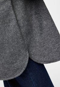 Γκρι υφασμάτινο ύφασμα που κρέμεται κομψά, με στρογγυλή ακμή. Συνδυάζεται με σκούρο τζιν, προσφέροντας αντίθεση με τις λεία επιφάνειες.