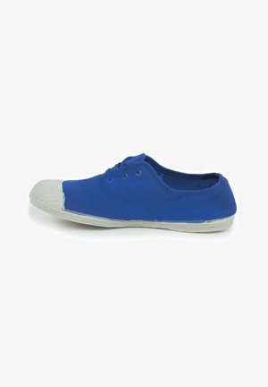 Blå kanvas sneakers med en hvid gummitå, der har tre øjer til snørebånd og en tekstureret sål. Lavprofil design.