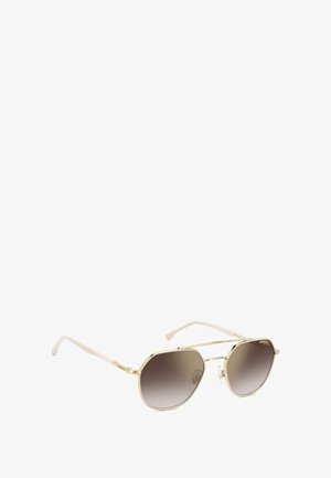 Lunettes de soleil à monture en métal doré avec des verres octogonaux, teinte brun dégradé et branches en plastique blanc. Présente un logo subtil sur la branche.