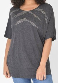 Šedý top s krátkými rukávy a kulatým výstřihem, který má na přední straně texturovaný design s malými tečkami vytvářejícími vzor. Měkká tkanina s uvolněným střihem.