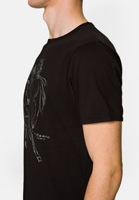 Czarny bawełniany t-shirt z grafiką konia w jasnoszarym kolorze z przodu. Regularny krój z krótkimi rękawami i okrągłym dekoltem.