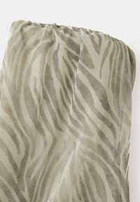 Tissu vert clair avec un motif zèbre effet velours, plié et froncé sur le bord supérieur.