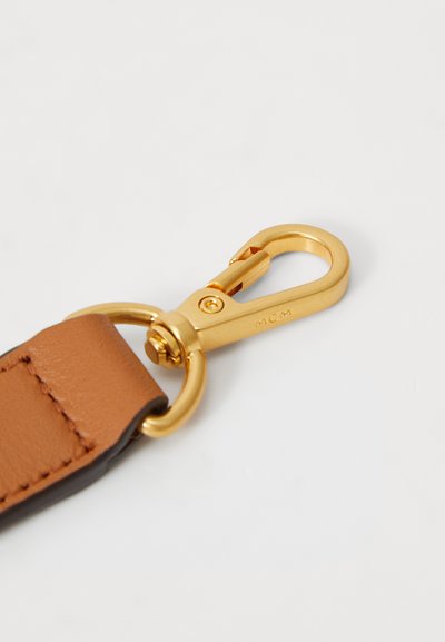 Mousqueton en métal doré attaché à une sangle en cuir beige avec un surpiqure visible sur fond blanc.
