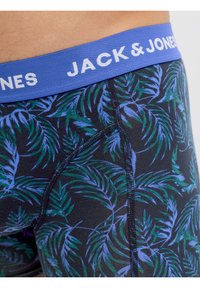 Κοντινό πλάνο ανδρικών εσωρουχων boxer με μπλε και πράσινο τροπικό φυλλώδες σχέδιο και μπλε ζώνη μέσης με την ετικέτα "JACK & JONES".