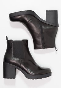 Zwarte leren enkellaarzen met een hoge blokhak, elastische zijpanelen en een ritsdetail. De zool is gestructureerd voor grip.