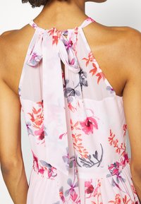 Blommig maxiklänning med rosa bas, som har livfulla röda och grå blommor, halterneck och knytning i ryggen för justerbar passform.