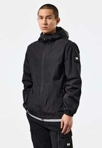 Black lightweight jacket with a hood, full front zipper, elastic cuffs, side pockets, and a small patch on the left sleeve.