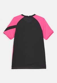 Kortärmad atletisk tröja med svart kropp och ljusrosa raglanärmar, med en kurvad fåll och plattlås sömmar.