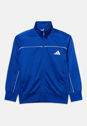 Modrá sportovní bunda na zip s bílým pruhem přes hrudník a rukávy, vysokým límcem a bílým trojúhelníkovým logem na levé straně hrudníku.