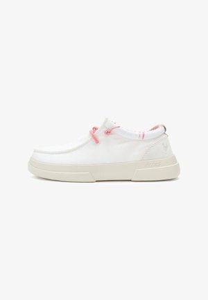 White canvas shoe with pink accents, featuring a low-profile design, rounded toe, and rubber sole with textured surface for grip.