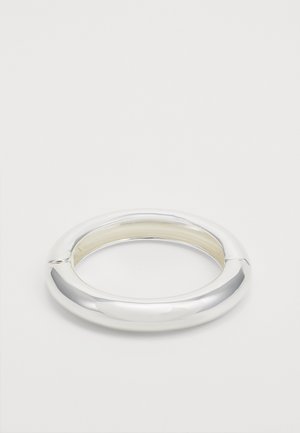Zilveren cirkelvormige bangle-armband met een gladde, glanzende afwerking en een open segment, reflecterend licht, minimalistisch ontwerp.