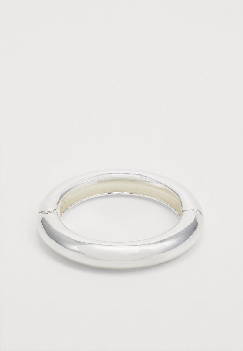 Brățară din argint de formă circulară, cu o suprafață netedă și strălucitoare și o secțiune deschisă, reflectând lumina, design minimalist.