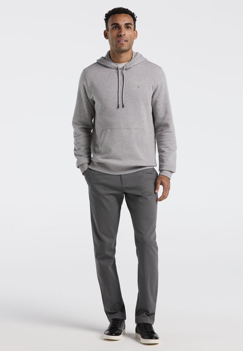 Haut à capuche gris clair avec une poche kangourou, un capuchon à cordon et un logo. Associé à un pantalon gris foncé et des baskets noires. Texture lisse sur l'ensemble.
