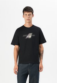 Zwarte katoenen t-shirt met korte mouwen en een ronde hals, voorzien van een logo in witte en metallic kleuren gedrukt op de borst.