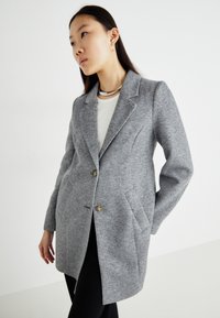 Manteau en mélange de laine grise au design ajusté, fermeture à un seul bouton, deux poches à l'avant et col à revers.