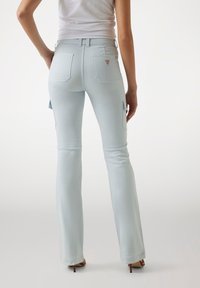 Jeans azzurri chiari con un design svasato, dotati di due tasche posteriori e tasche laterali sicure. Realizzati in un materiale denim con una superficie liscia.