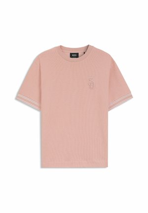 Camiseta de manga corta de color rosa claro con cuello redondo, con doble raya blanca en los puños de las mangas y un pequeño logo "SG" bordado en el pecho.